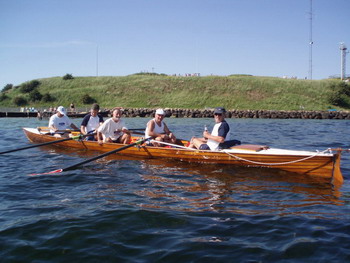 Vierer-Mannschaft im Riemenboot vor der Küste